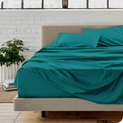 Microfiber sheets on a bed with a brick wall behind it