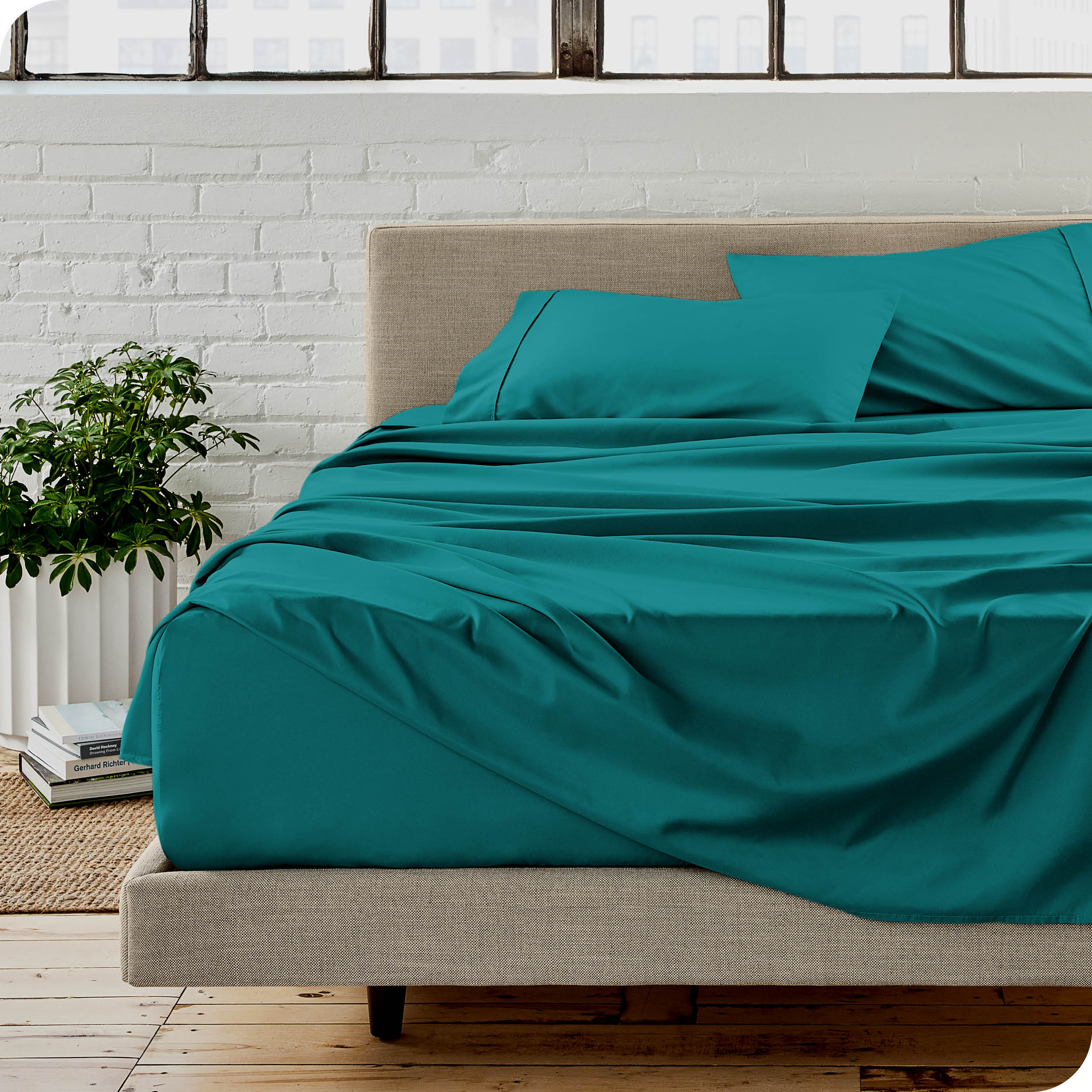 Microfiber sheets on a bed with a brick wall behind it
