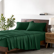 Modern bedroom with a bed against a white wall with a nightstand next to the bed. The bed has bamboo sheets draped over it.