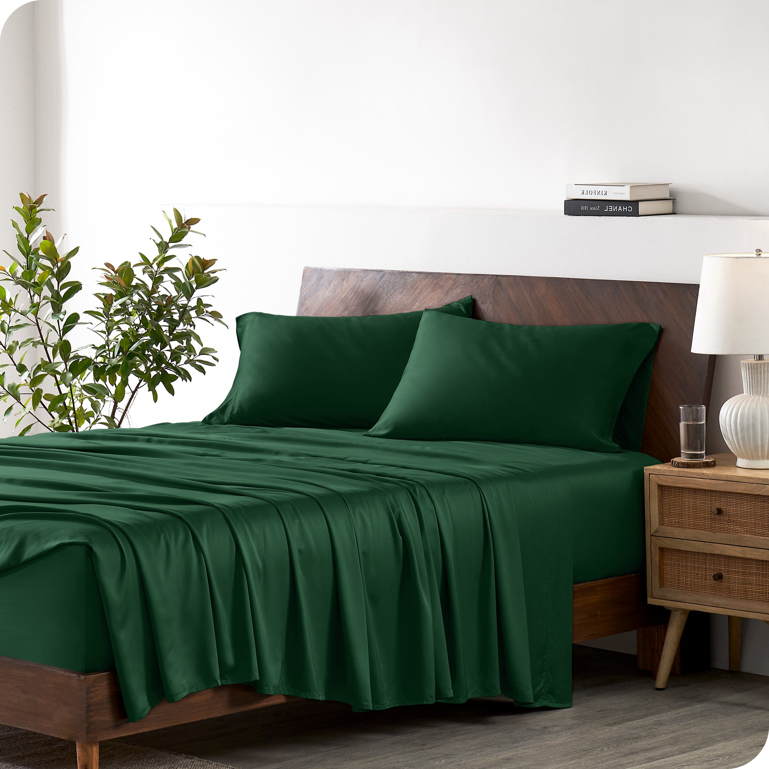 Modern bedroom with a bed against a white wall with a nightstand next to the bed. The bed has bamboo sheets draped over it.