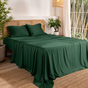 Bamboo sheets on a bed in a bedroom with plants and a window.