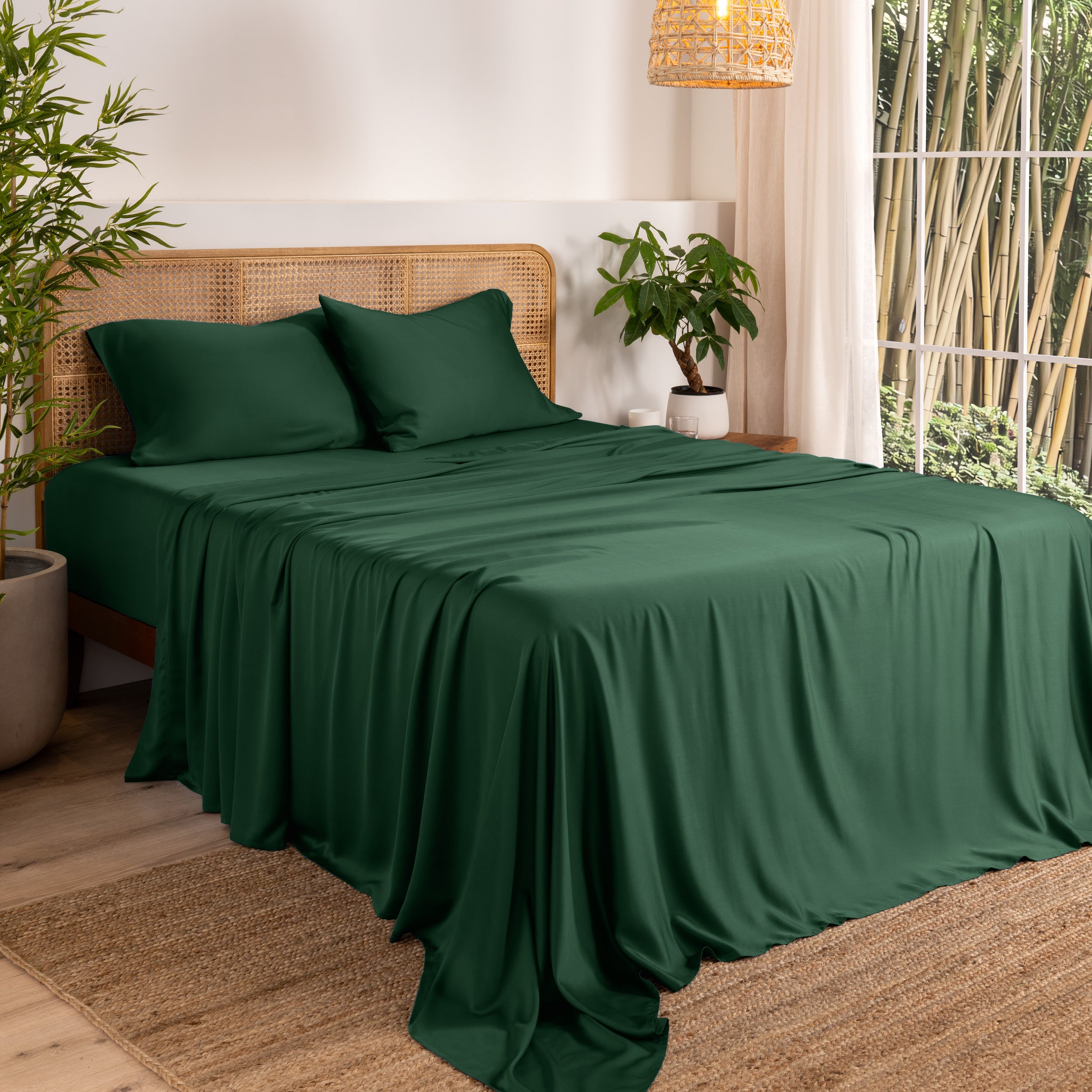 Bamboo sheets on a bed in a bedroom with plants and a window.