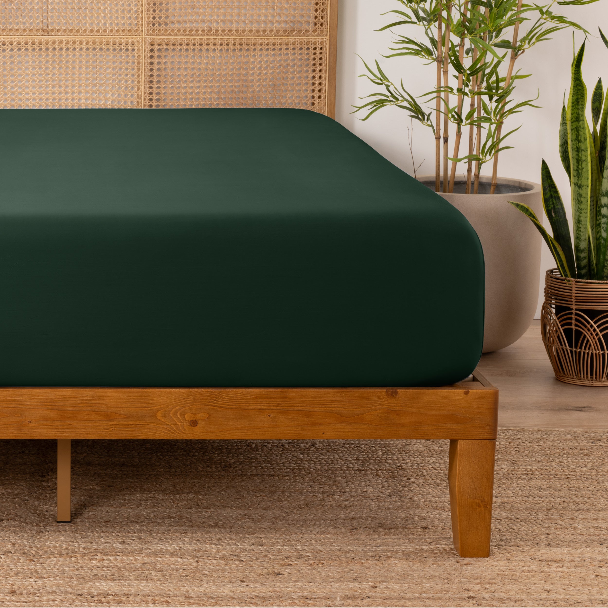 Bamboo fitted sheet on a wooden bed with plants in the background
