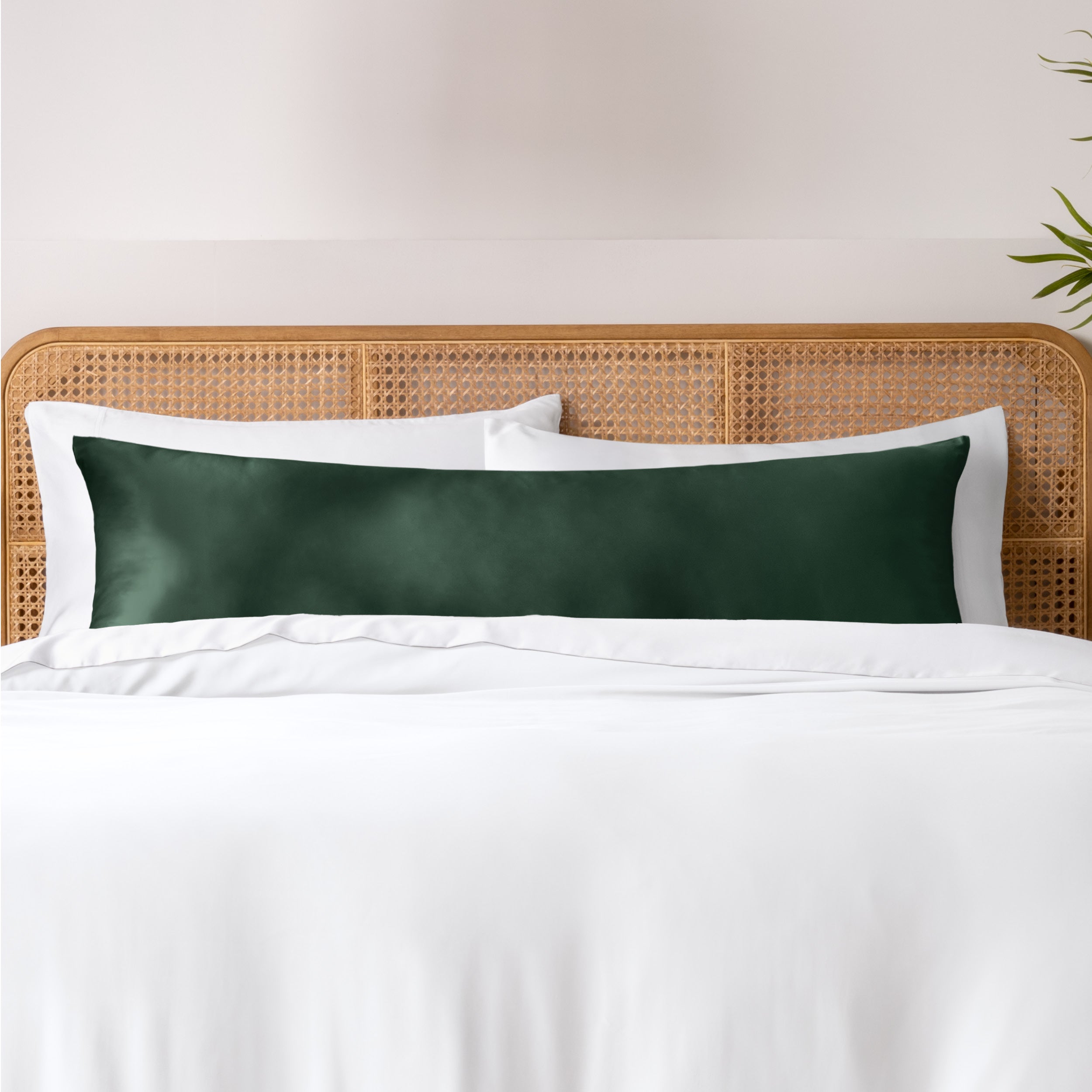 Bamboo body pillowcase on a bed with white bedding and a wicker headboard.