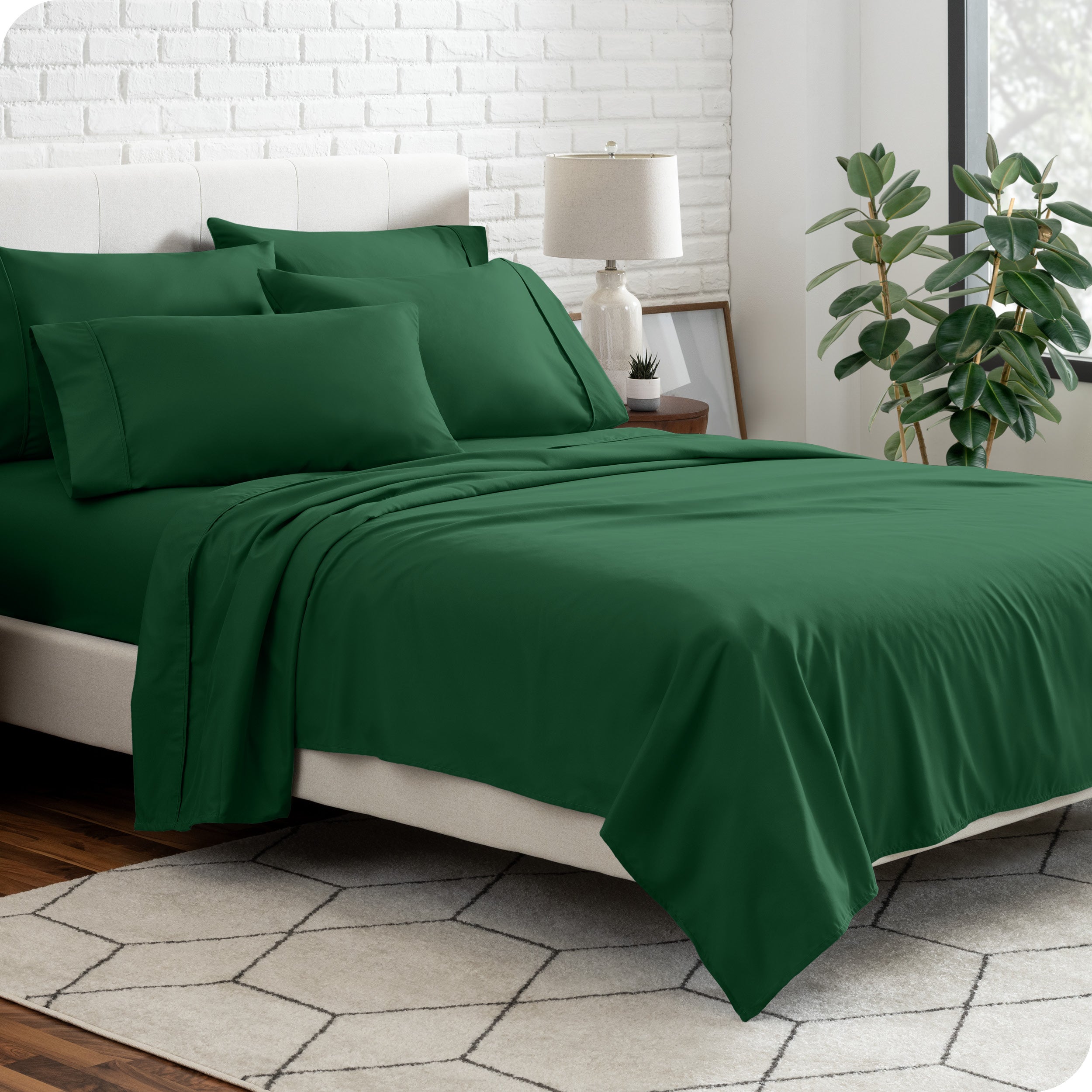 A bedroom setting with a bed made with the microfiber bed sheets and four pillows.