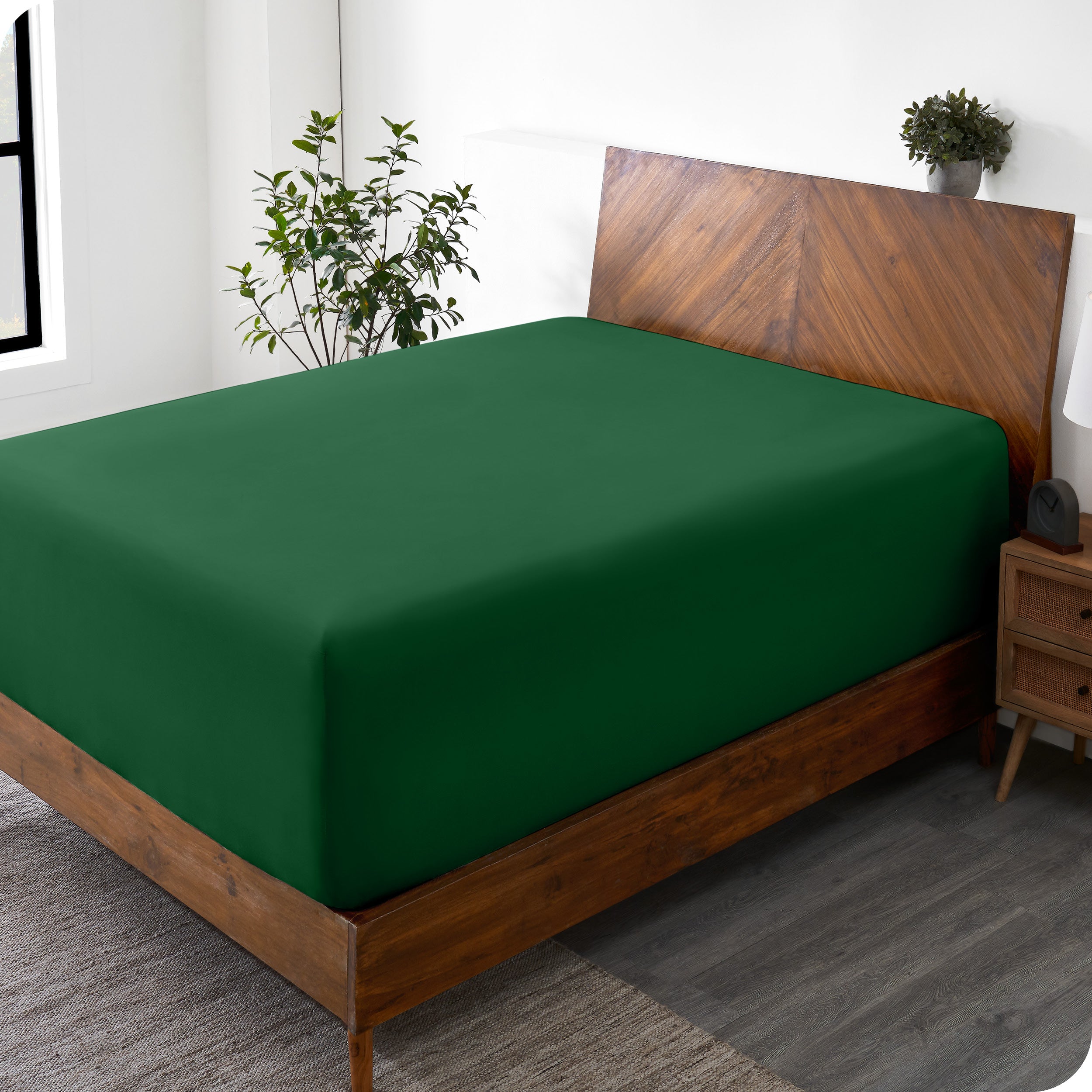 A wide corner view of a modern bed made with a microfiber fitted sheet on the mattress. 