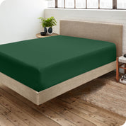 Corner view of a modern bed with a microfiber fitted sheet on the mattress. 