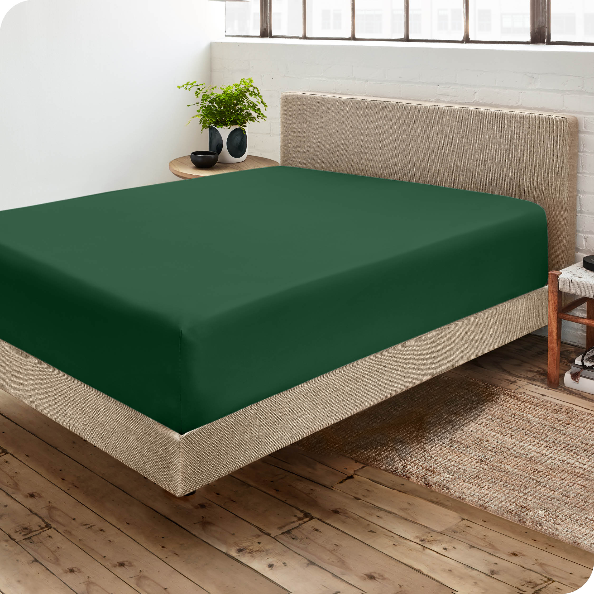 Corner view of a modern bed with a microfiber fitted sheet on the mattress. 