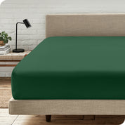 A bed with a microfiber fitted sheet on the mattress. 