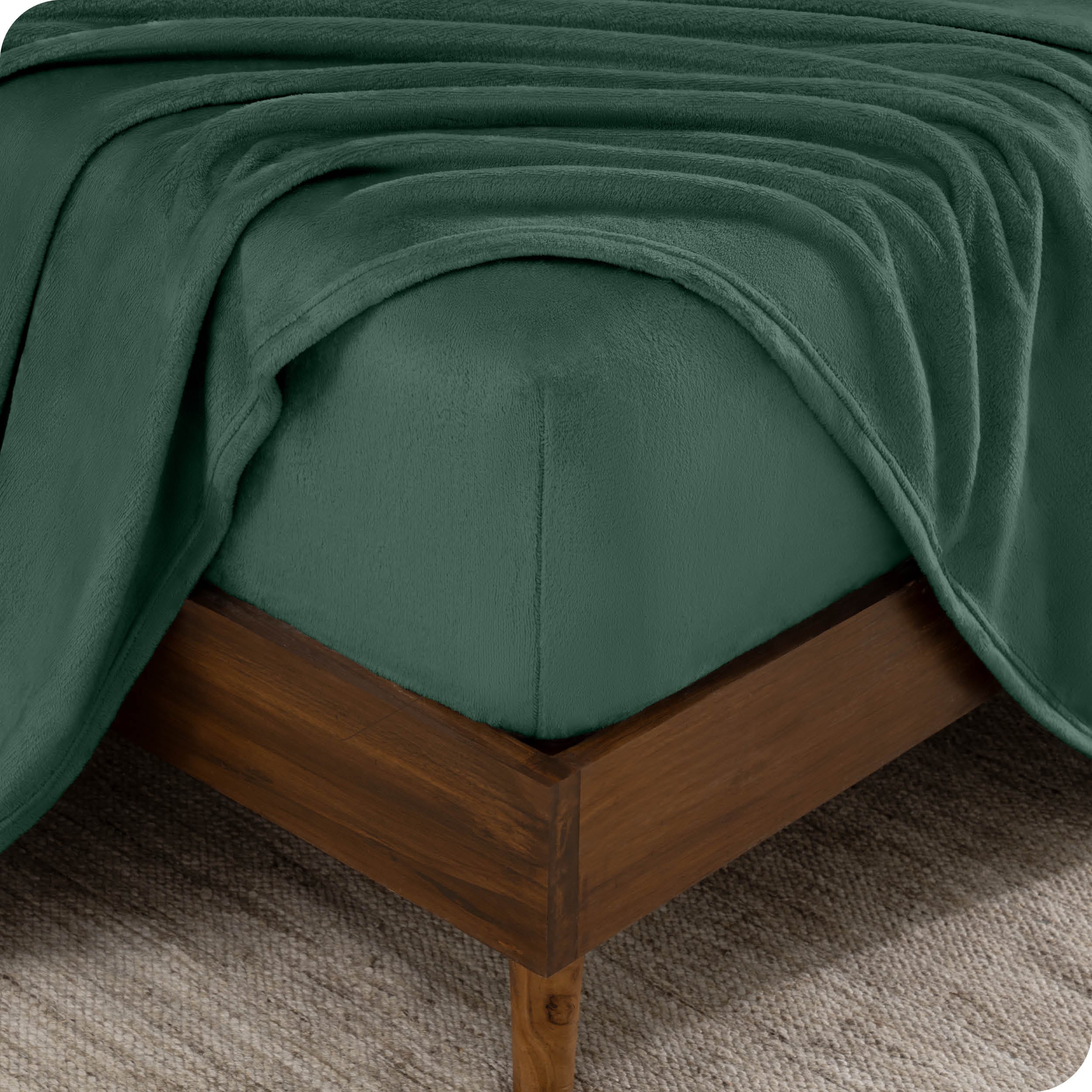 A corner of a mattress with a fitted sheet and a flat sheet on it.