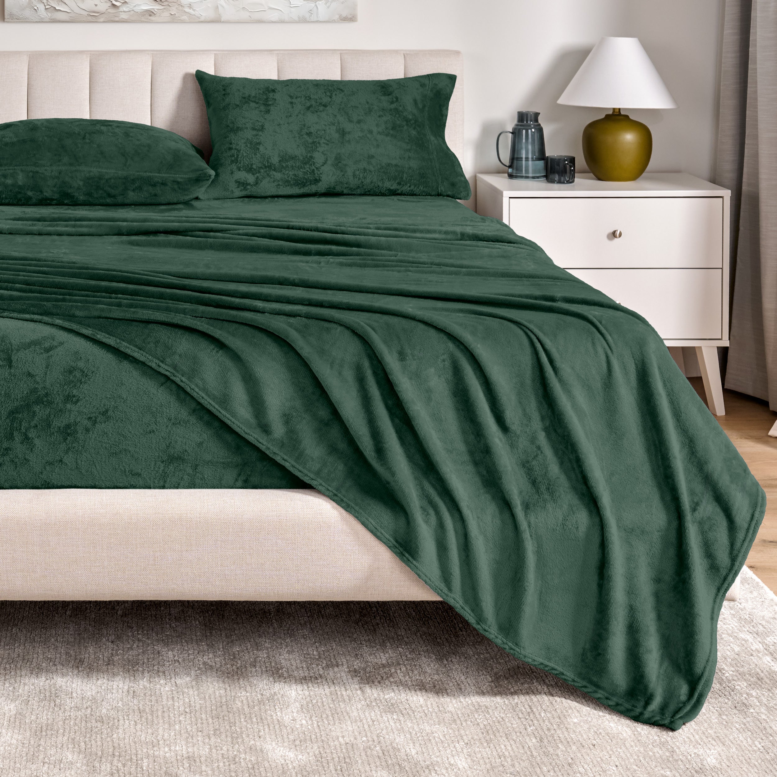 Microplush sheets on a bed in a bedroom setting with a nightstand and lamp.