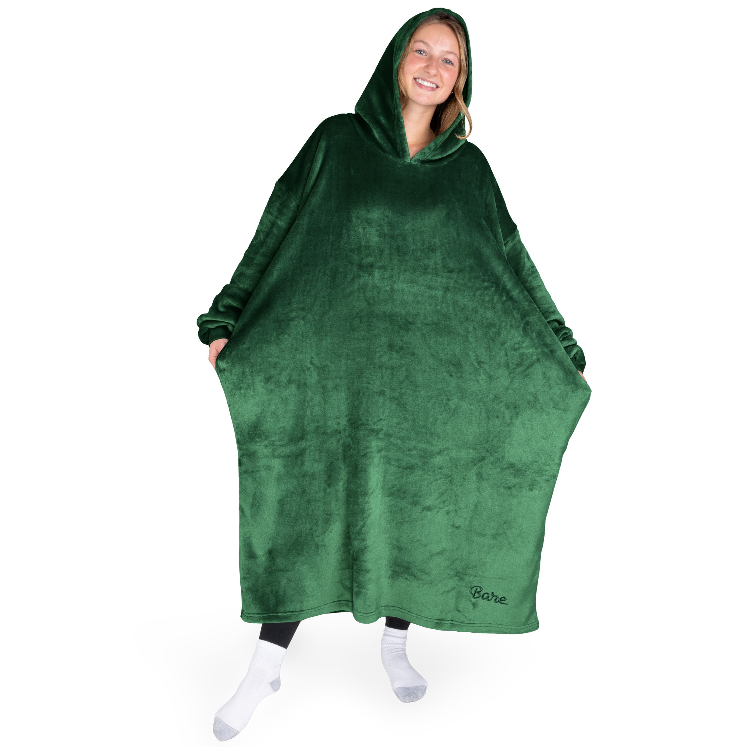 An adult is standing while wearing a long microplush wearable blanket