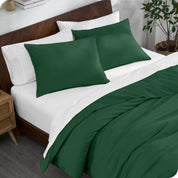 A bed made with an organic jersey duvet cover, pillow sham covered pillows and extra pillows