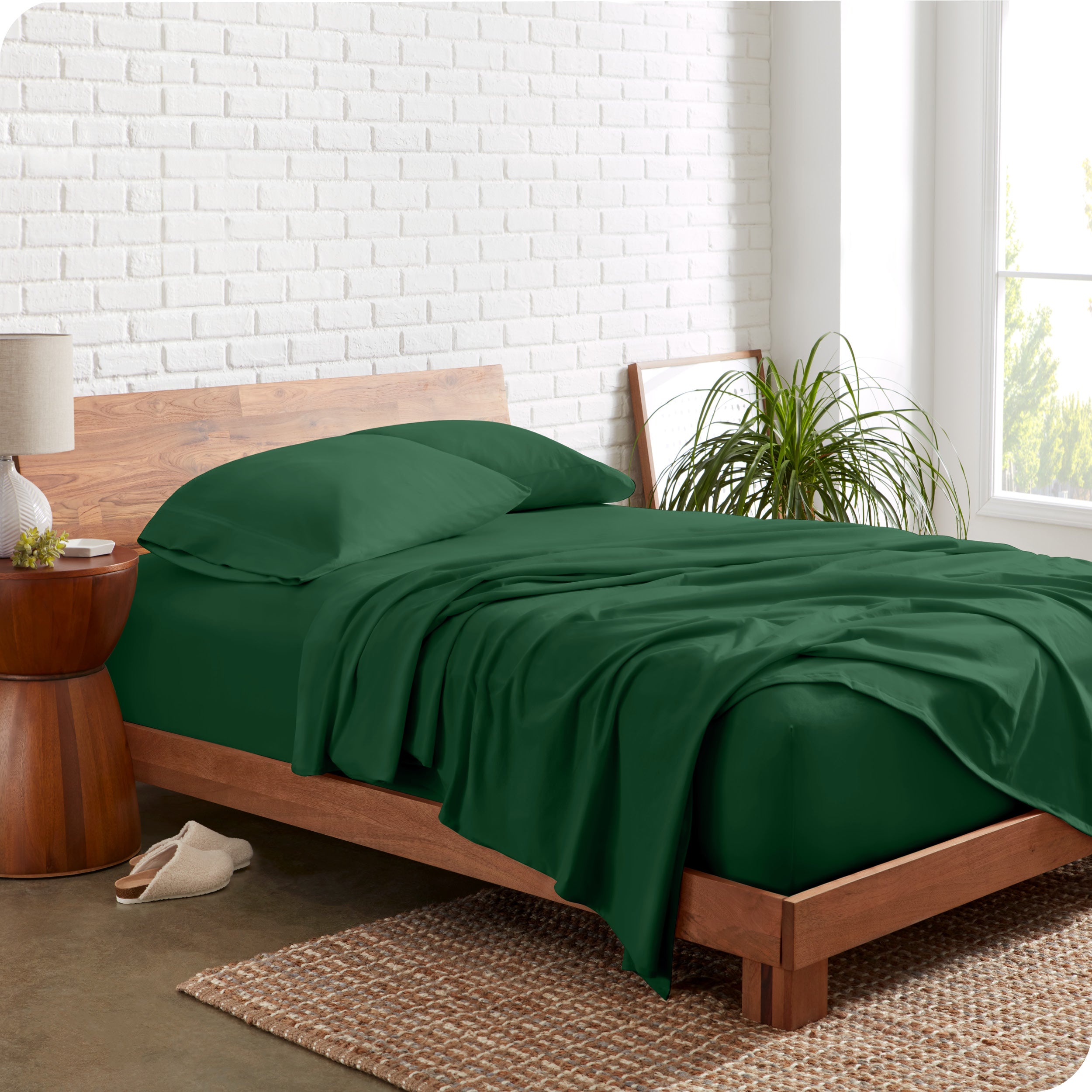 Organic jersey sheets on a bed with a brick wall behind the headboard