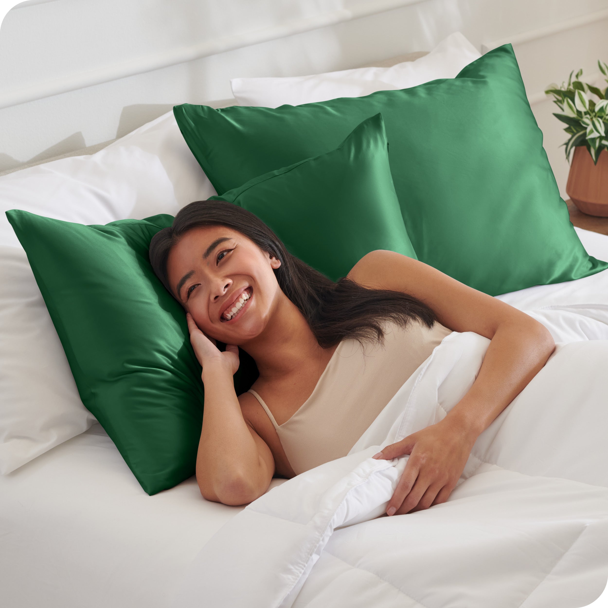 A woman in bed with her head resting on a silk pillowcase covered pillow
