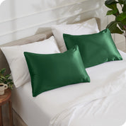 2 satin pillowcases on pillows leaning against other pillows on a bed