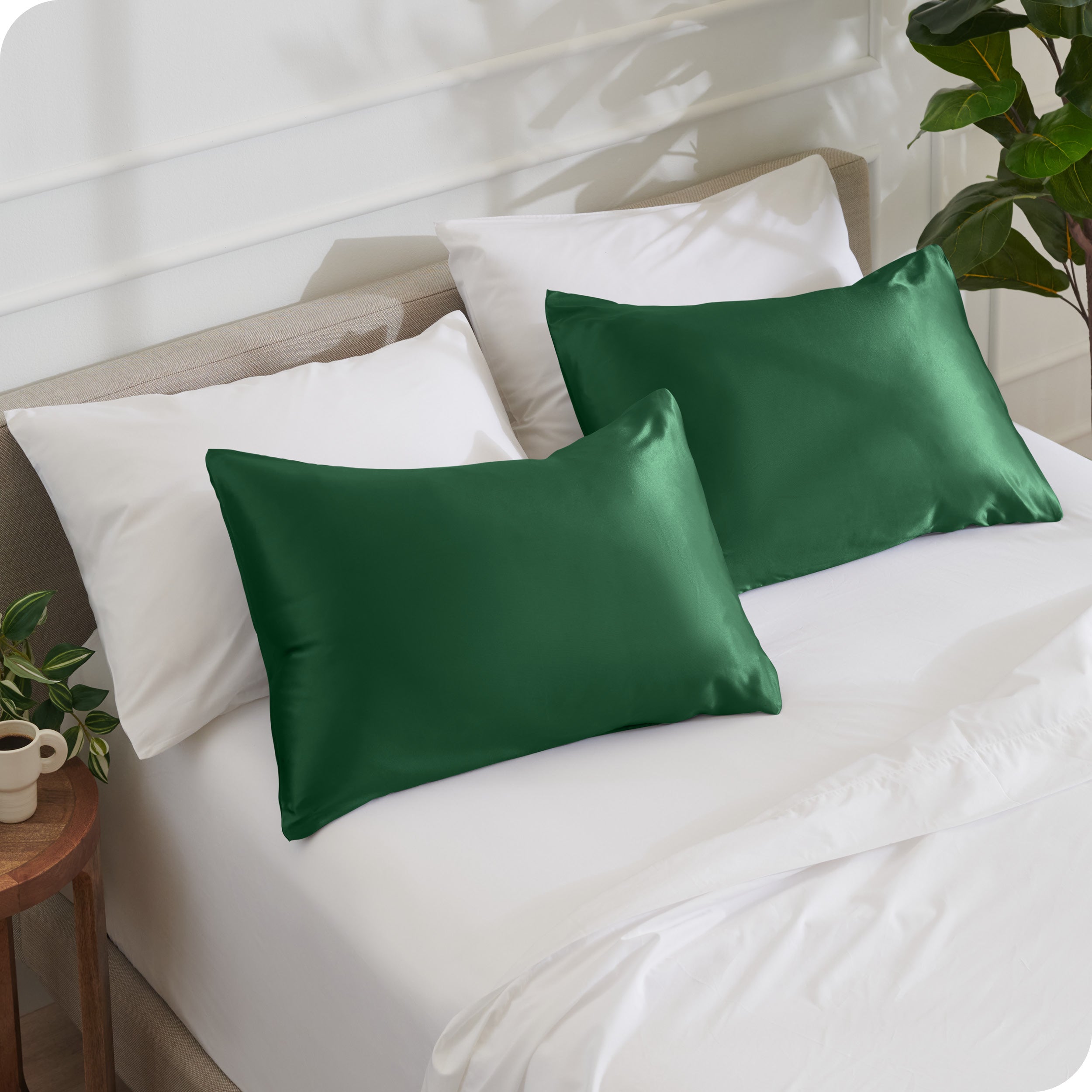 2 satin pillowcases on pillows leaning against other pillows on a bed