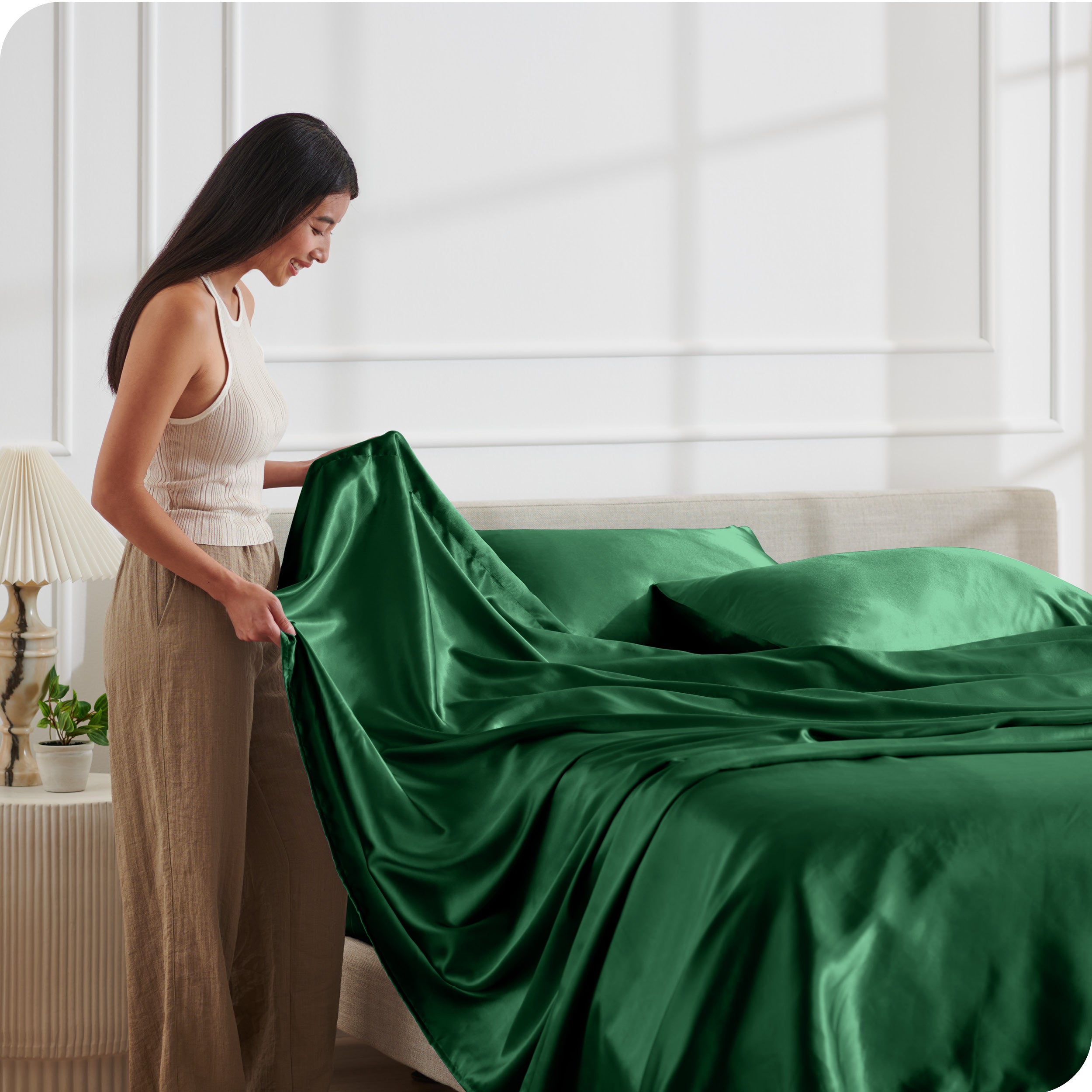A woman making a bed with satin sheets
