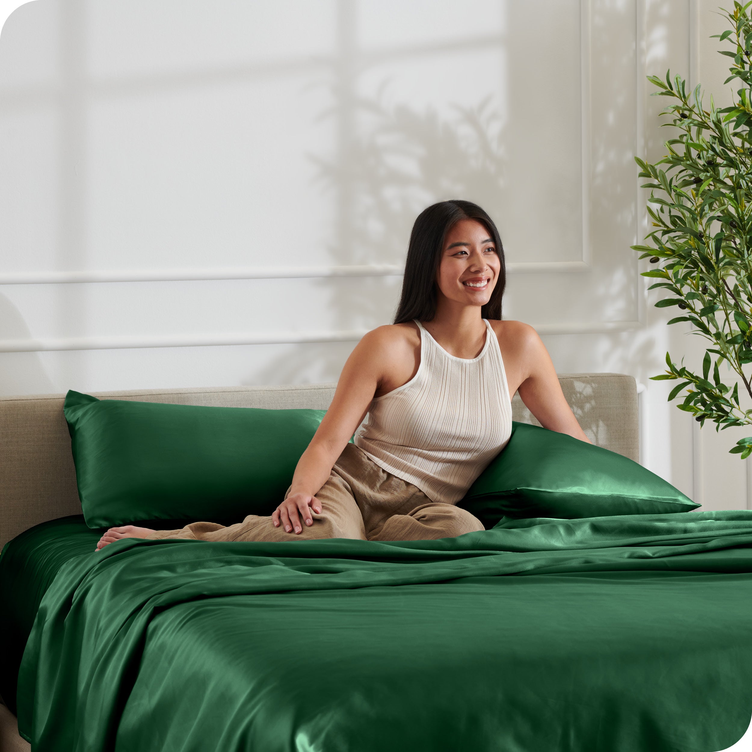 A woman sitting on a bed made with satin sheets