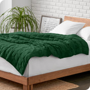 A cotton weighted blanket is loosely draped over a bed