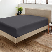 Corner view of a modern bed with a microfiber fitted sheet on the mattress. 