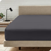 A bed with a microfiber fitted sheet on the mattress. 