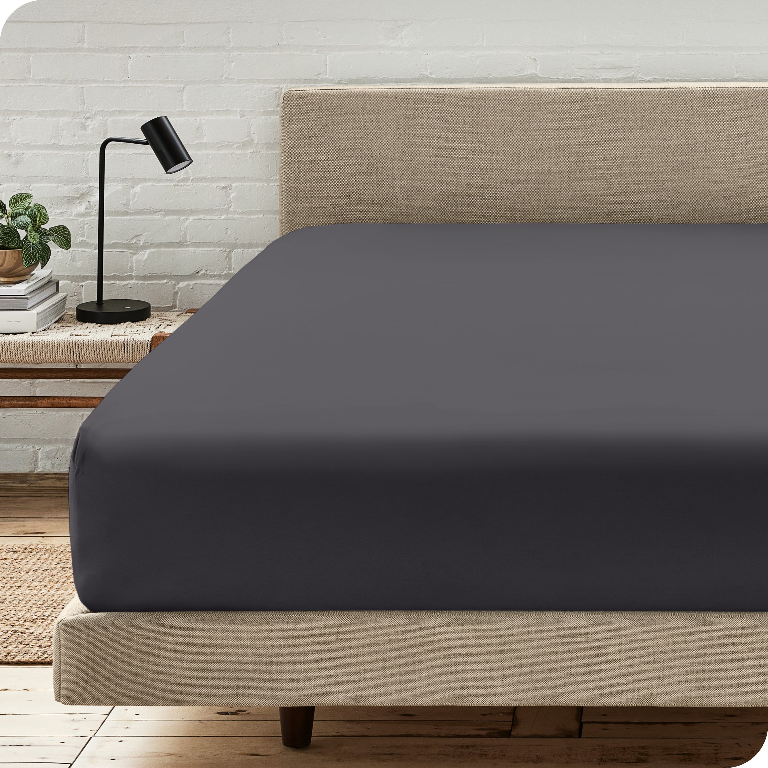 A bed with a microfiber fitted sheet on the mattress. 
