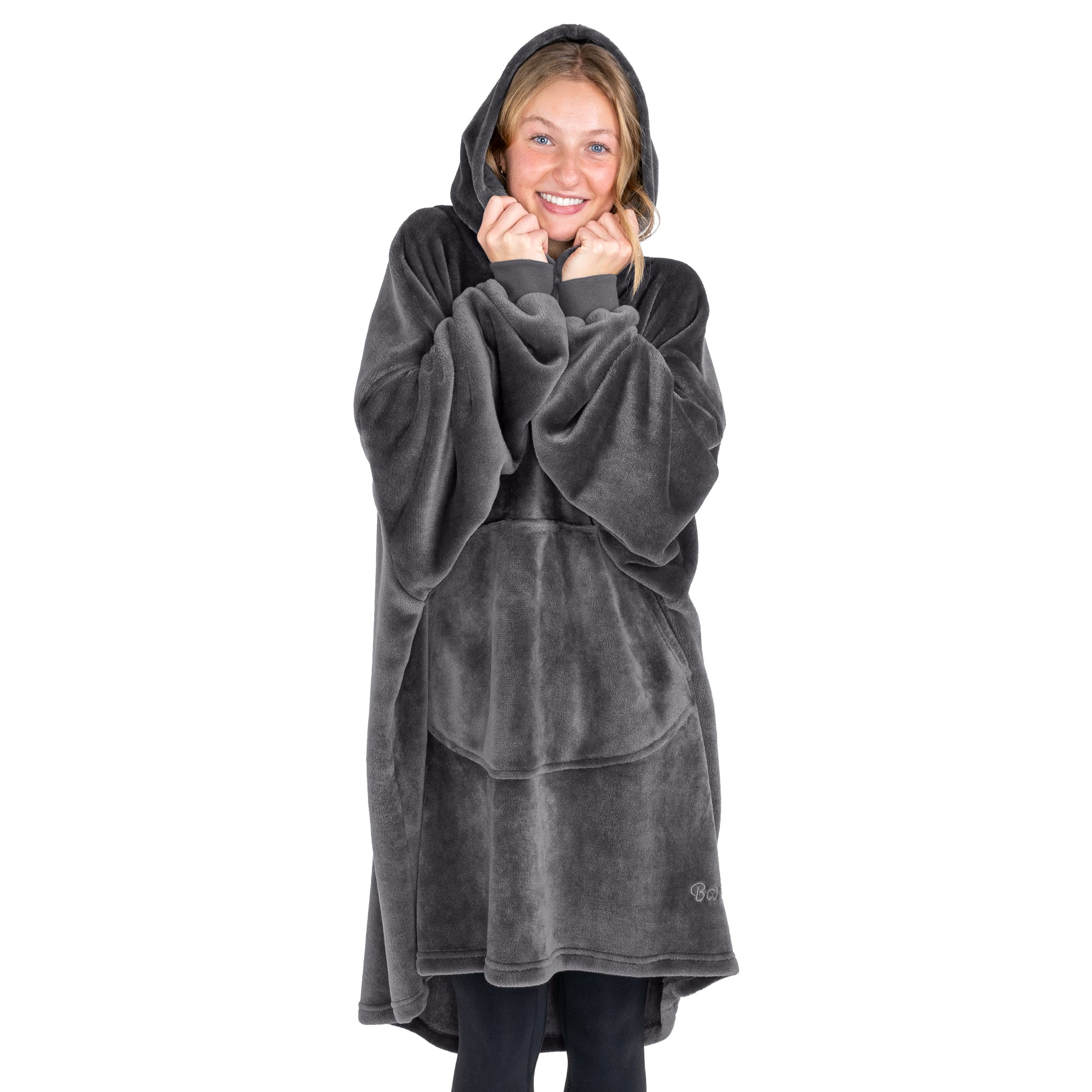 A woman is snuggled up in a hooded microplush wearable blanket