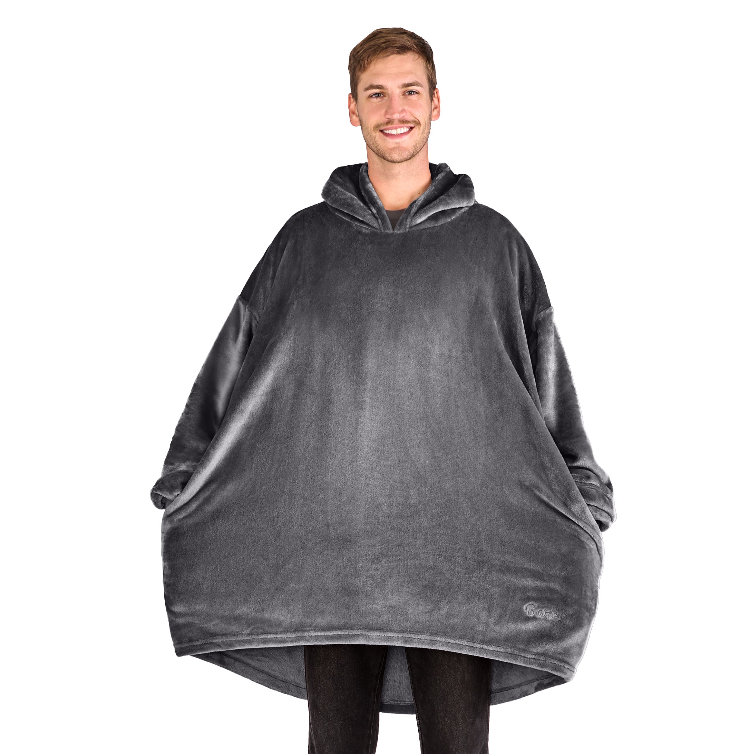 A man has a microplush wearable blanket on and his hands are in the side pockets