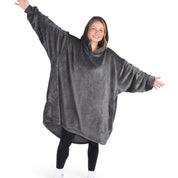 A woman is standing with her arms stretched out and has a hooded wearable blanket on