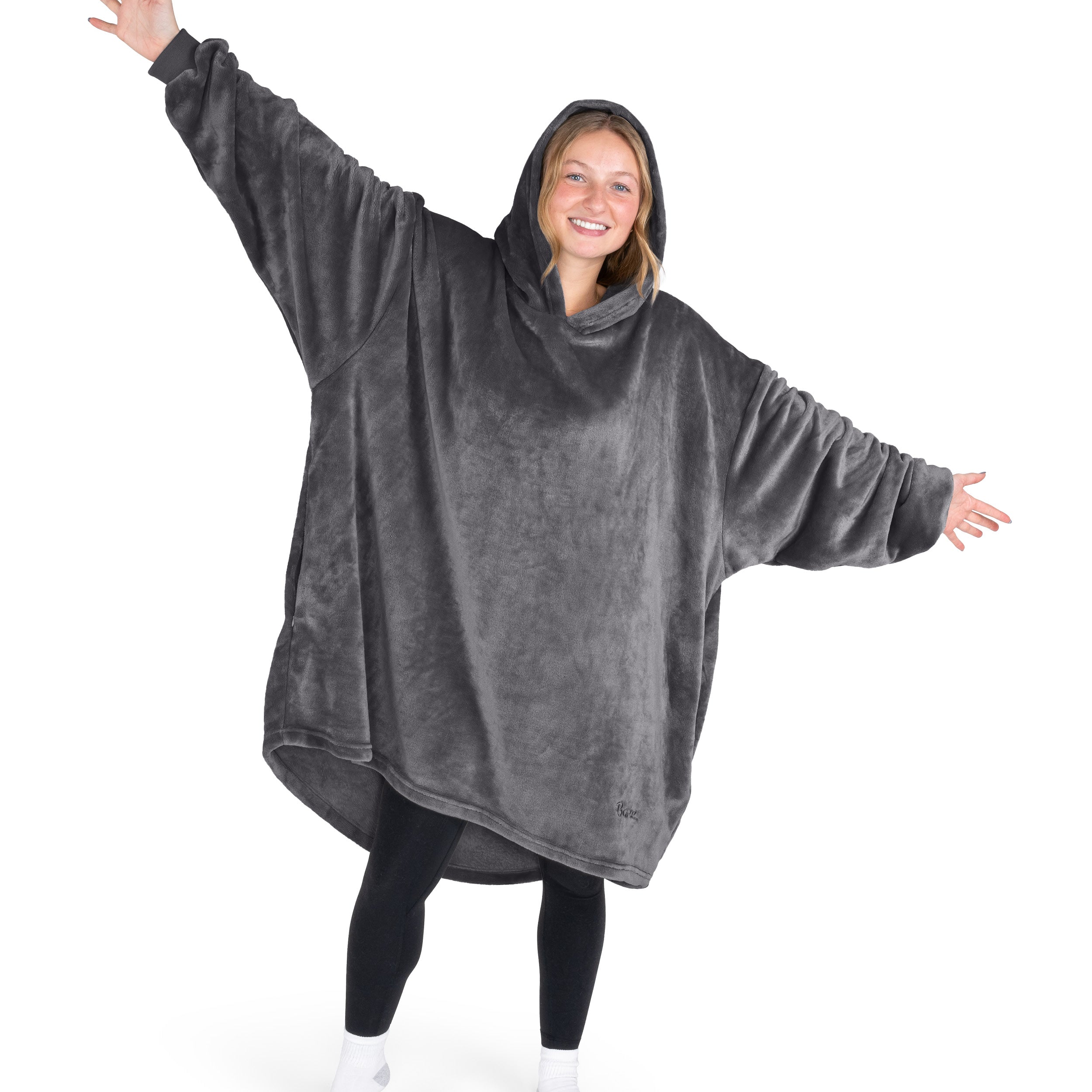A woman is standing with her arms stretched out and has a hooded wearable blanket on