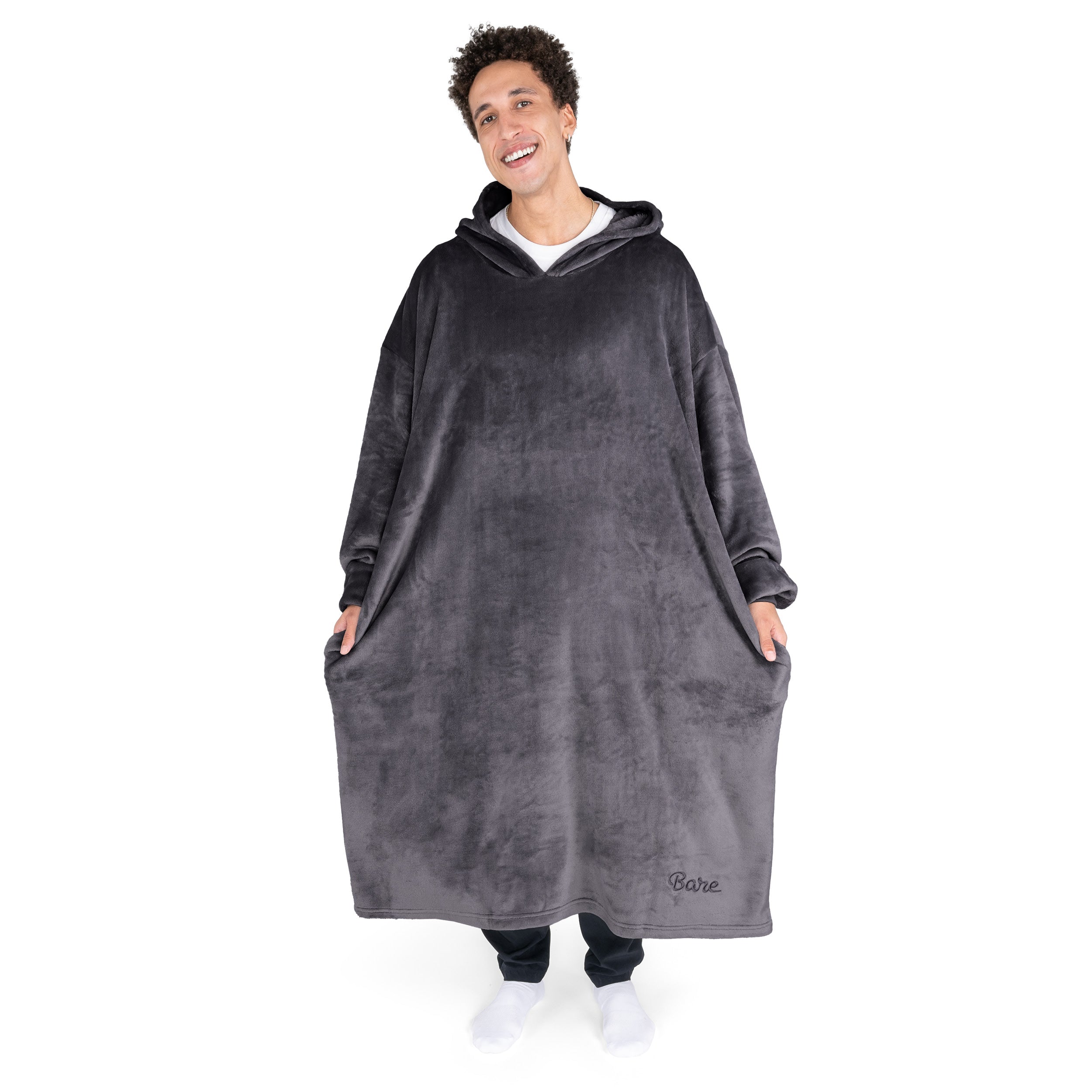 An adult is standing while wearing a long microplush wearable blanket