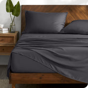 TENCEL™ sheet set on a bed with the flat sheet loosely draped over the top. The mattress is on a wooden bed frame.