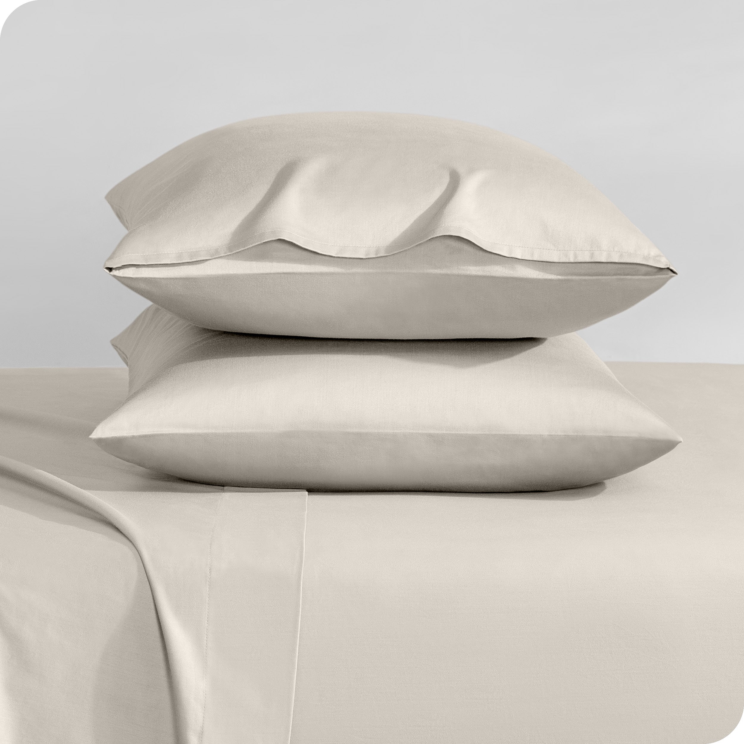 Two sateen pillowcases stacked on a bed