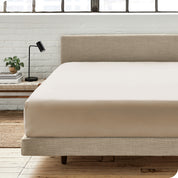 A percale fitted sheet on a bed with table next to it