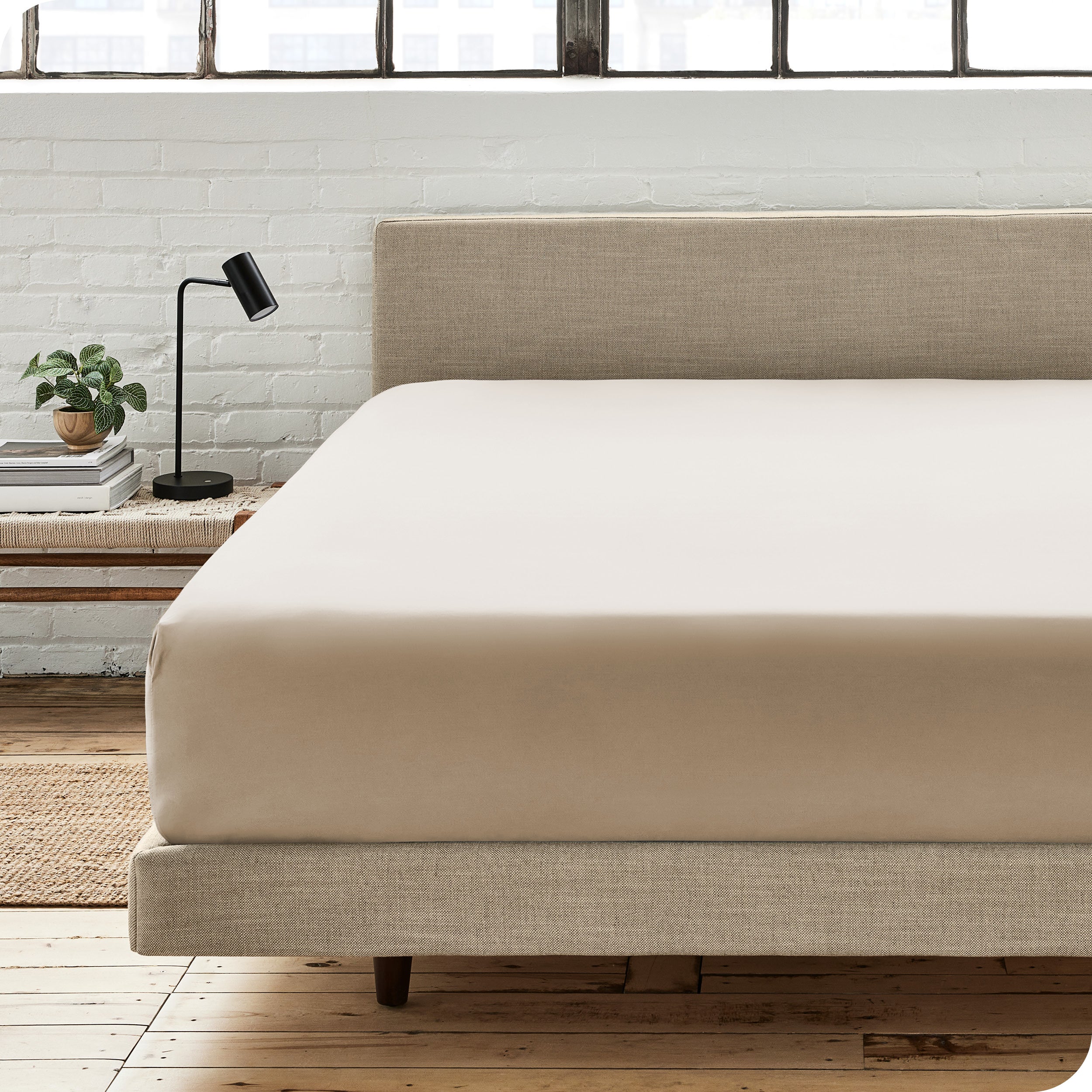 A percale fitted sheet on a bed with table next to it