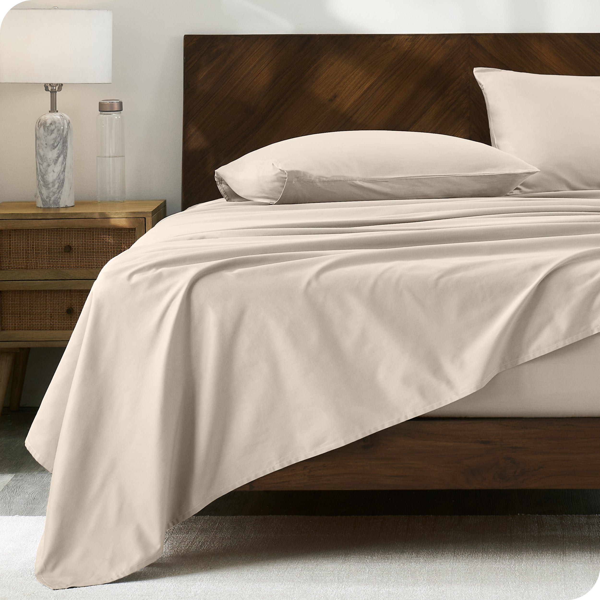 Percale sheet set on a bed with a wooden headboard