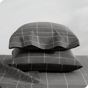 Two pillowcases on pillows stacked on a bed with matching sheets