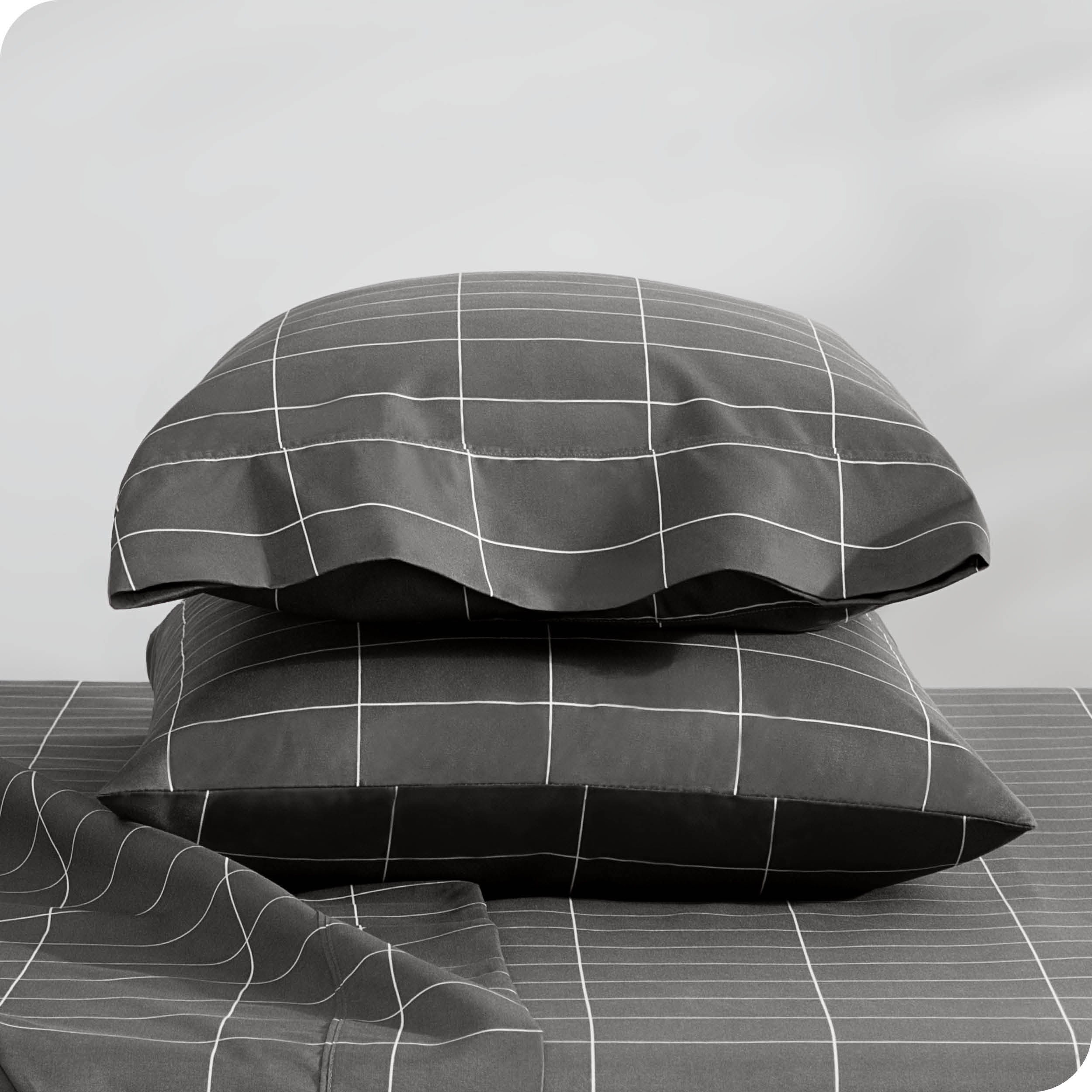 Two pillowcases on pillows stacked on a bed with matching sheets