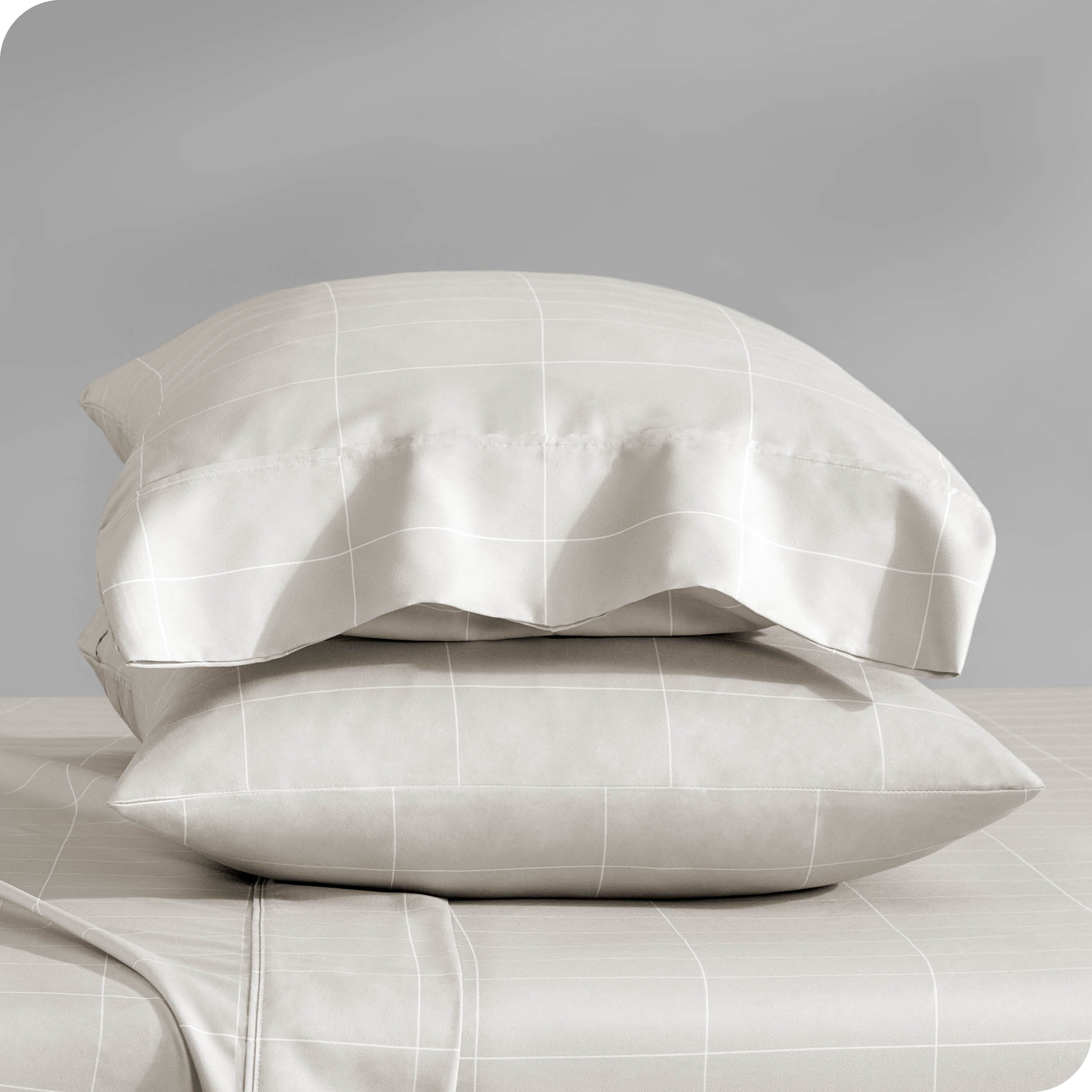 Two pillowcases on pillows stacked on a bed with matching sheets