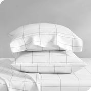 Two pillowcases on pillows stacked on a bed with matching sheets