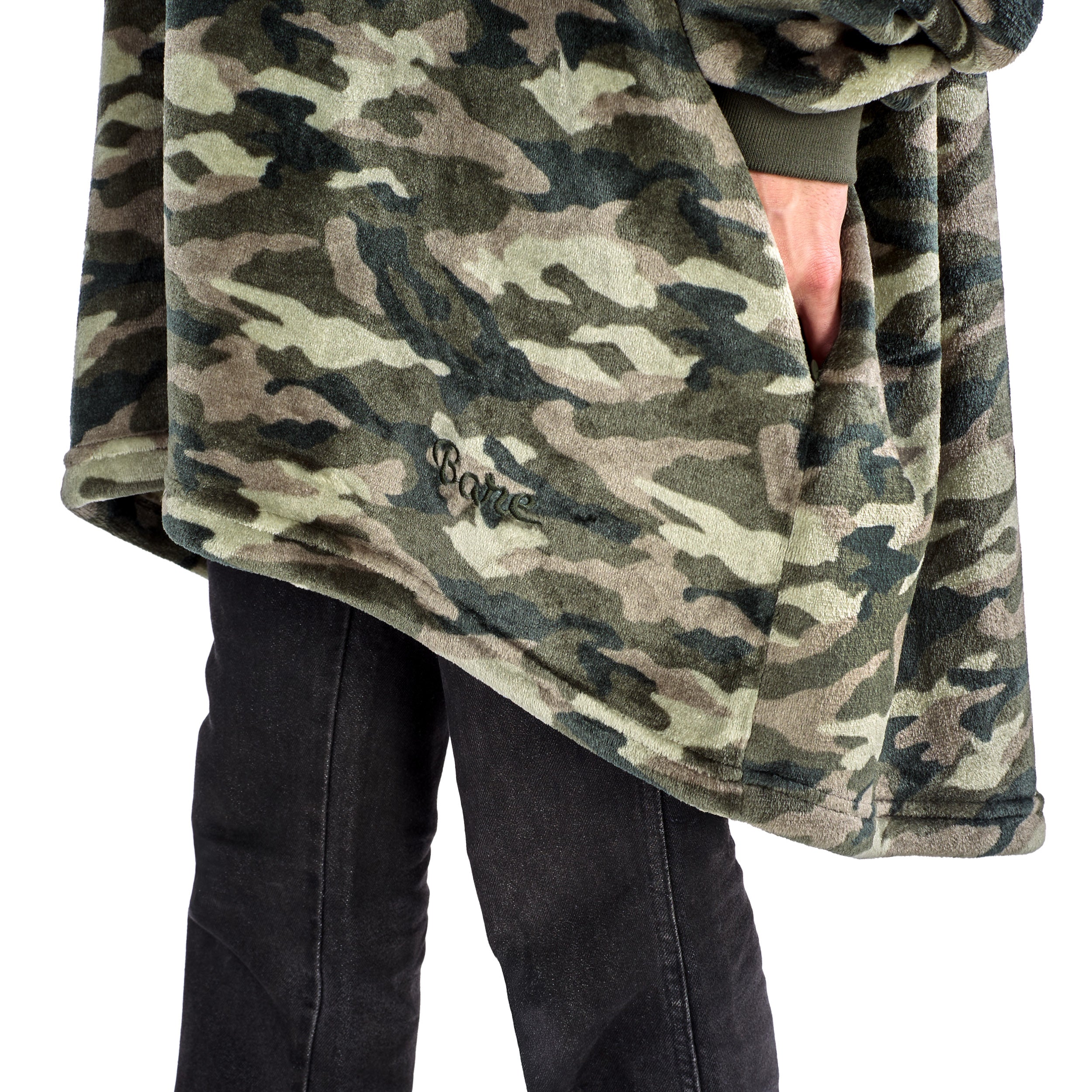 A man has a microplush wearable blanket on and his hands are in the side pockets