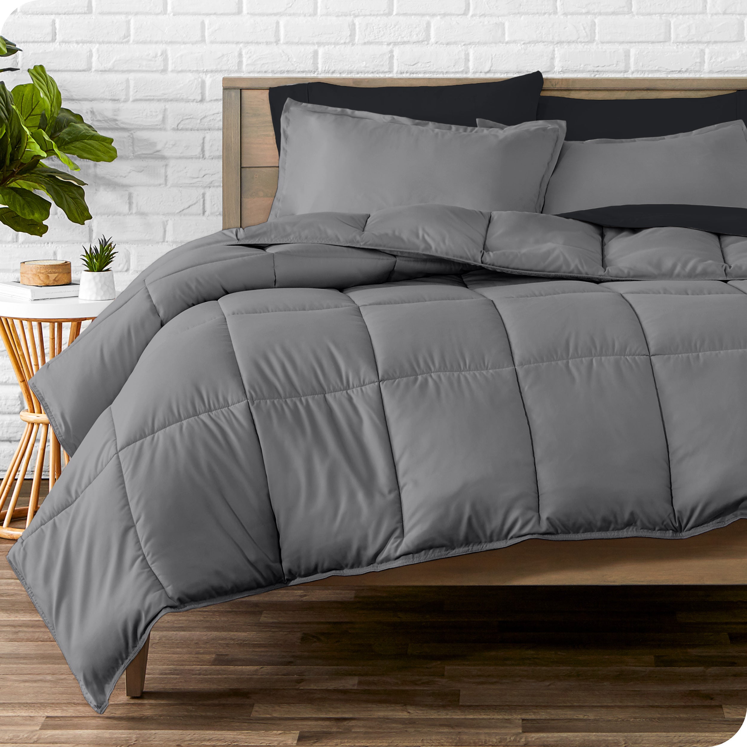 A wooden bed frame with sheets, pillow shams and a comforter on the bed