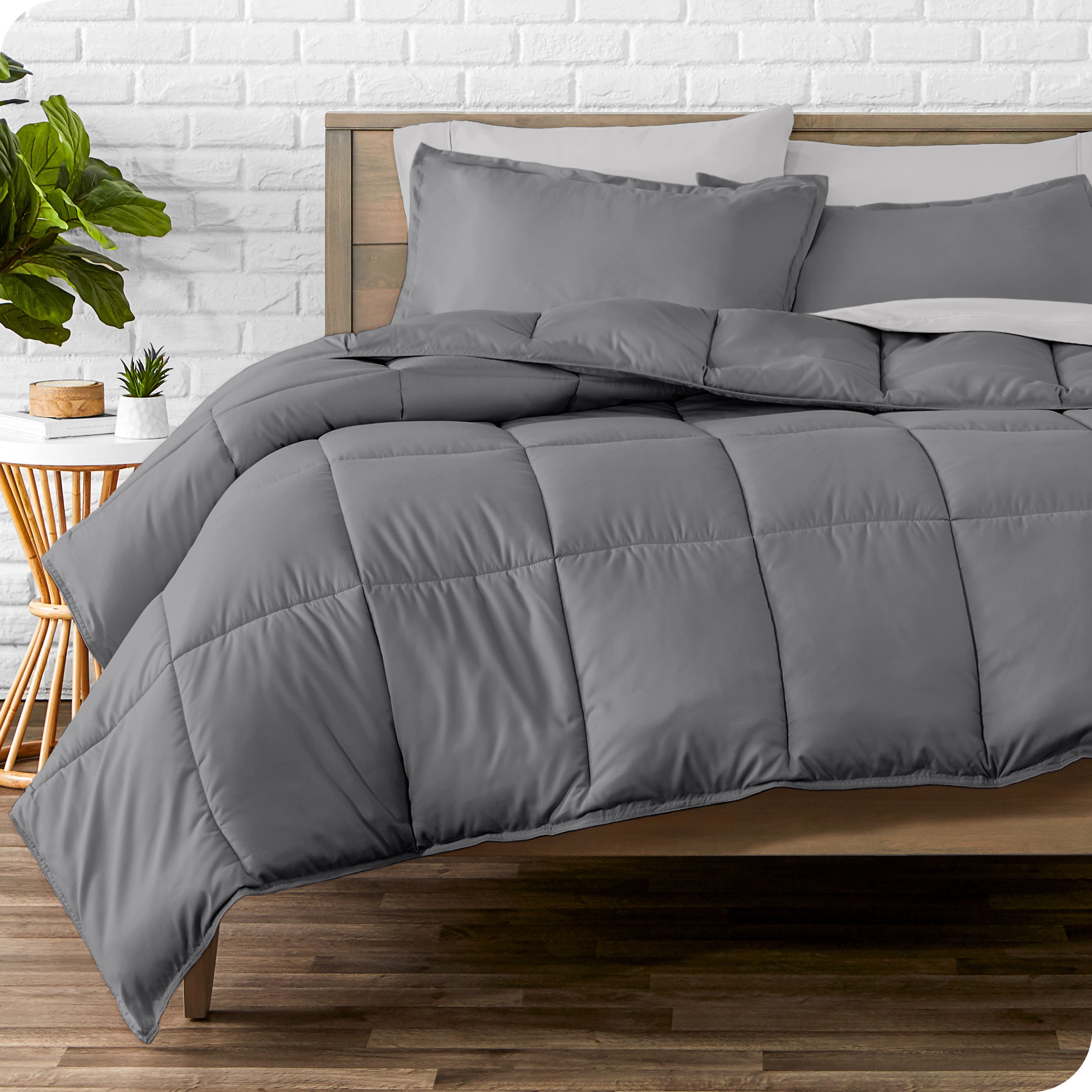 A wooden bed frame with sheets, pillow shams and a comforter on the bed
