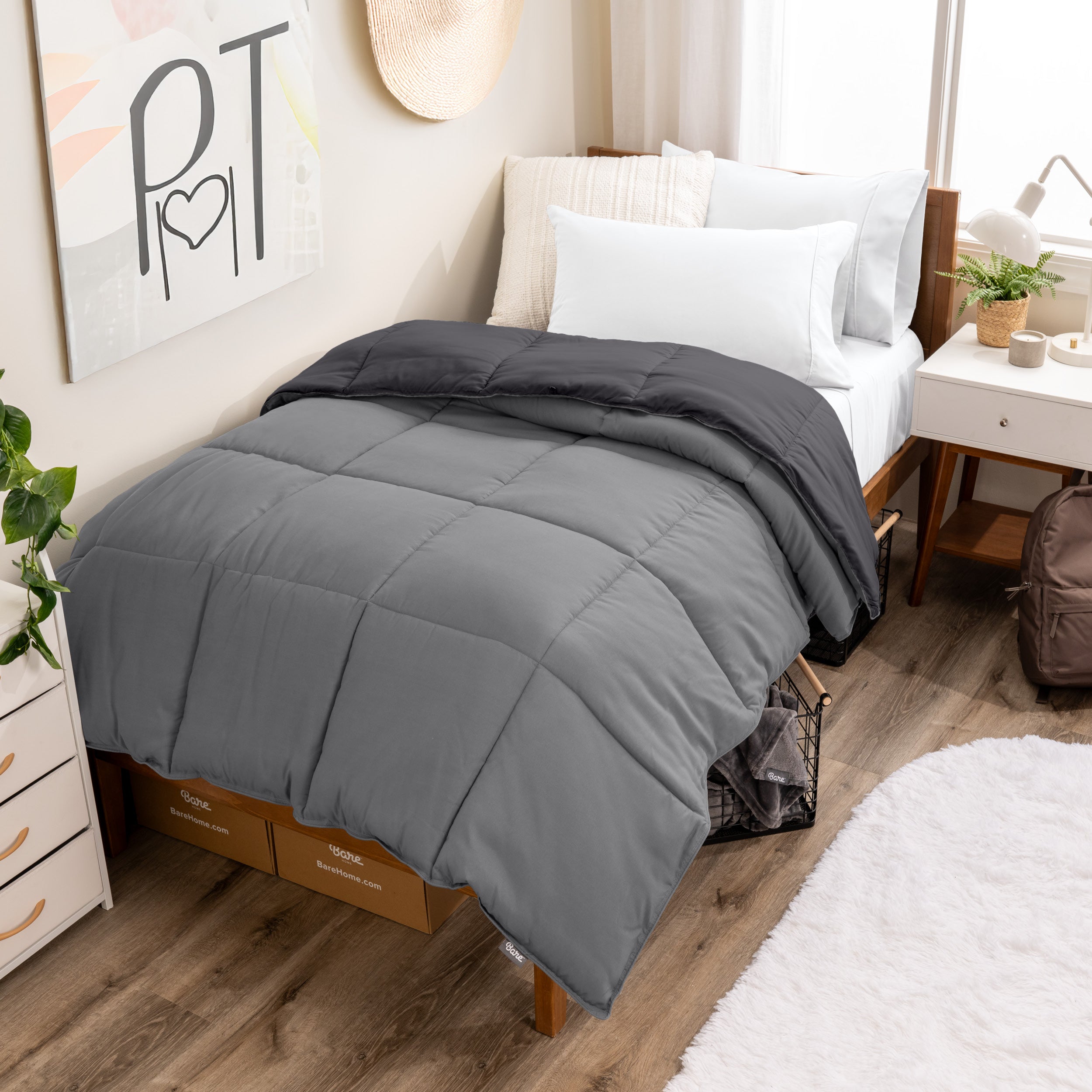 Wooden bed frame with a reversible comforter on the bed. The comforter is folded back over showing the two different colors.