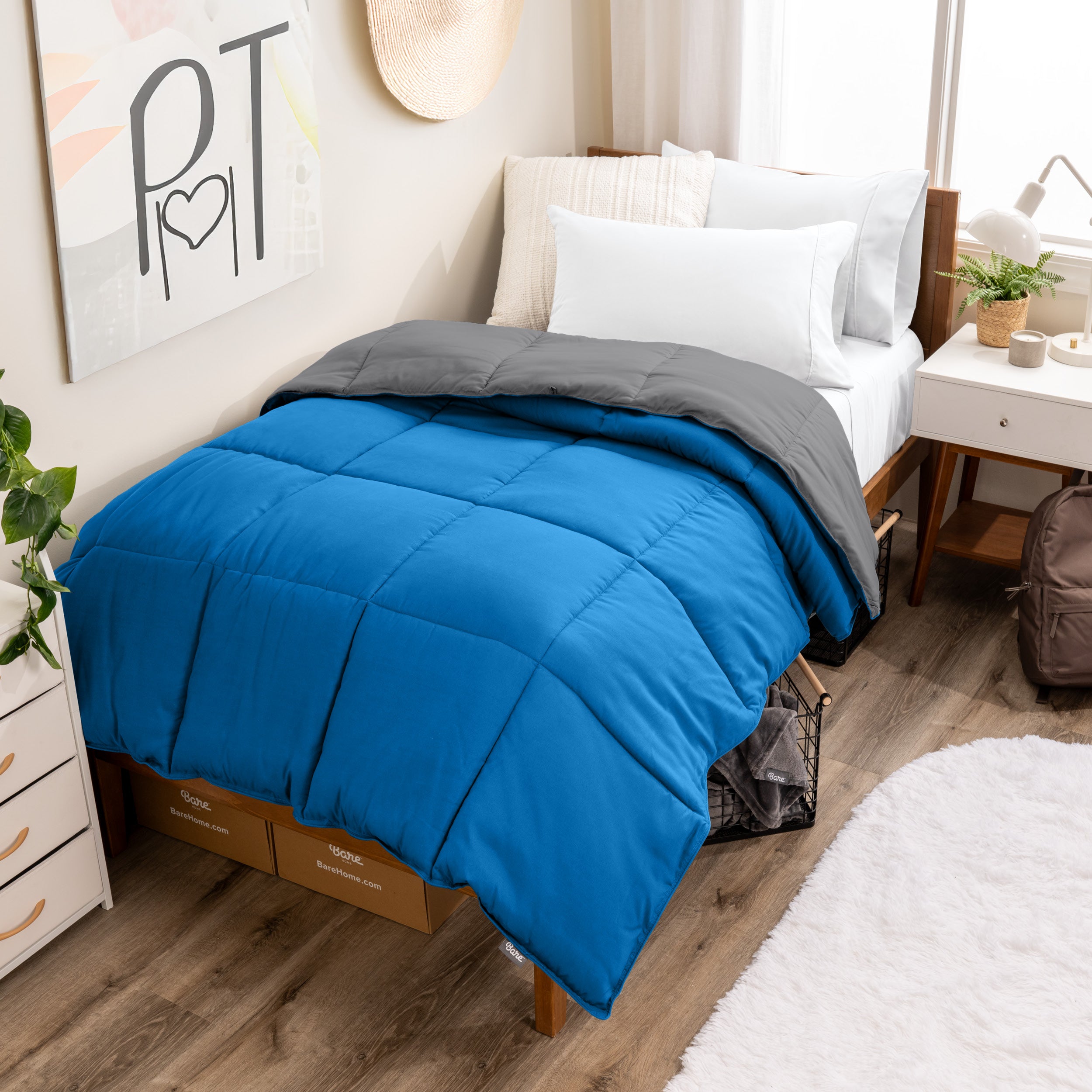 Wooden bed frame with a reversible comforter on the bed. The comforter is folded back over showing the two different colors.