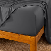 Bed sheets on a wooden bed frame with a brown carpet background