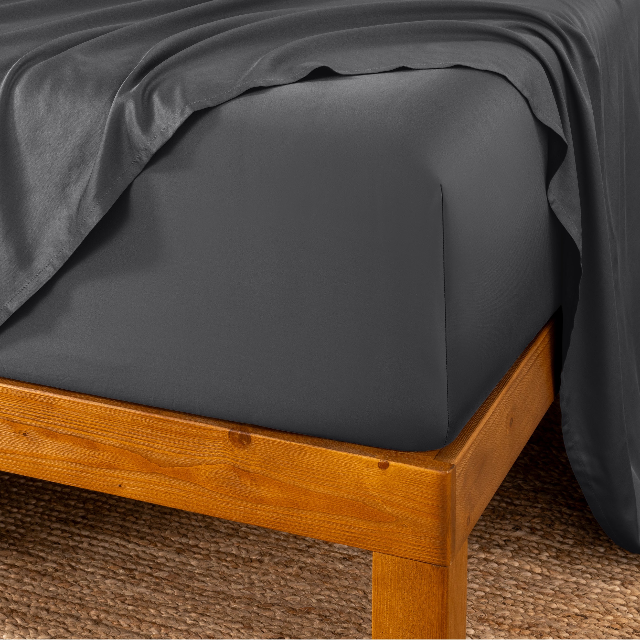 Bed sheets on a wooden bed frame with a brown carpet background