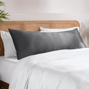 Bamboo pillowcase on a bed with white bedding and a wooden headboard.