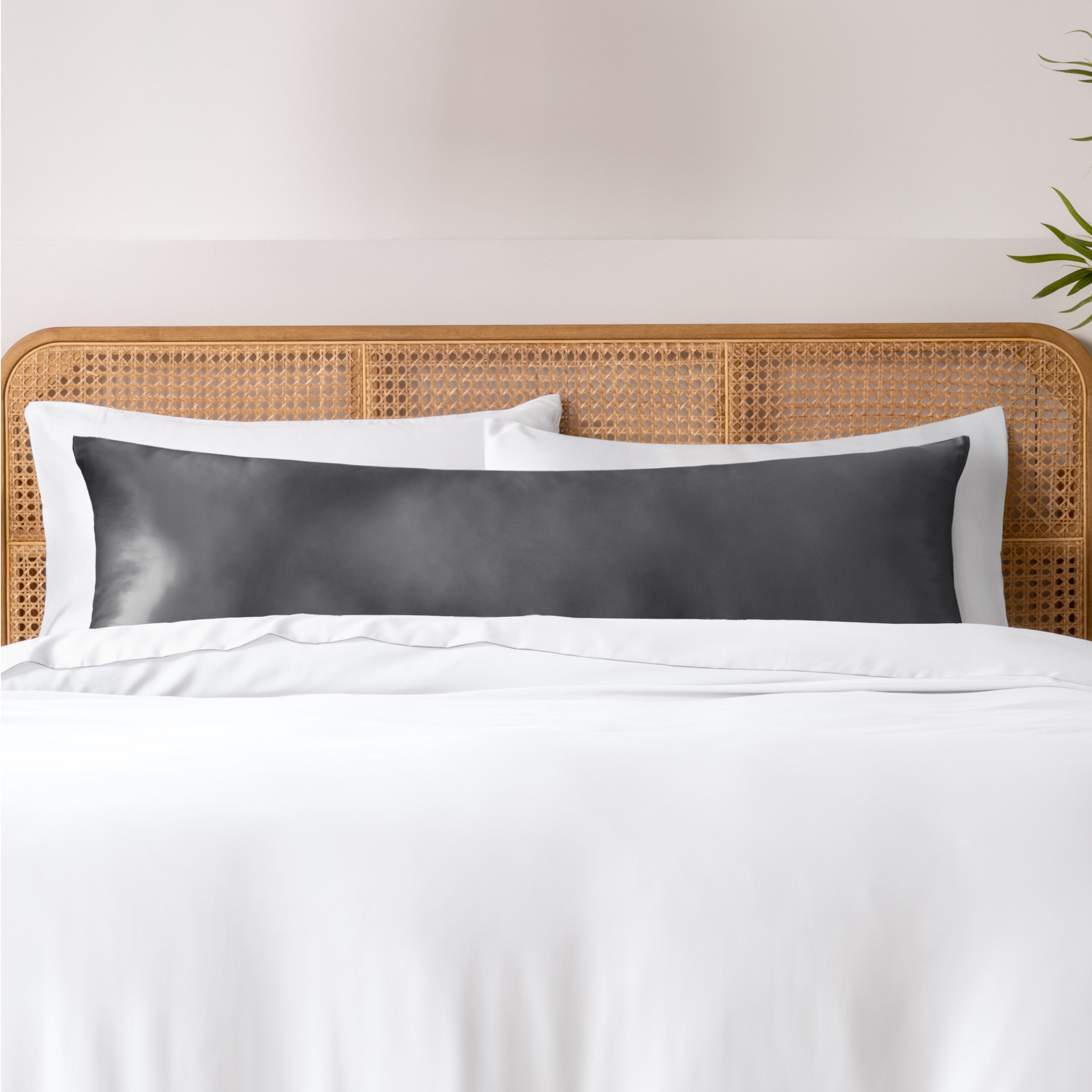 Bamboo body pillowcase on a bed with white bedding and a wicker headboard.
